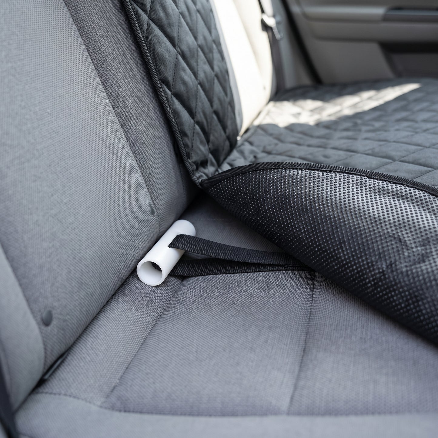 Close-up of the seat anchor tucked into the seat crease, showing the textured non-slip backing